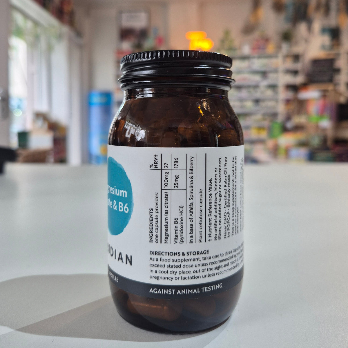 Bottle of Viridian Magnesium Citrate & B6 supplement on a white surface with a blurred store background with label on a white surface, blurred store background