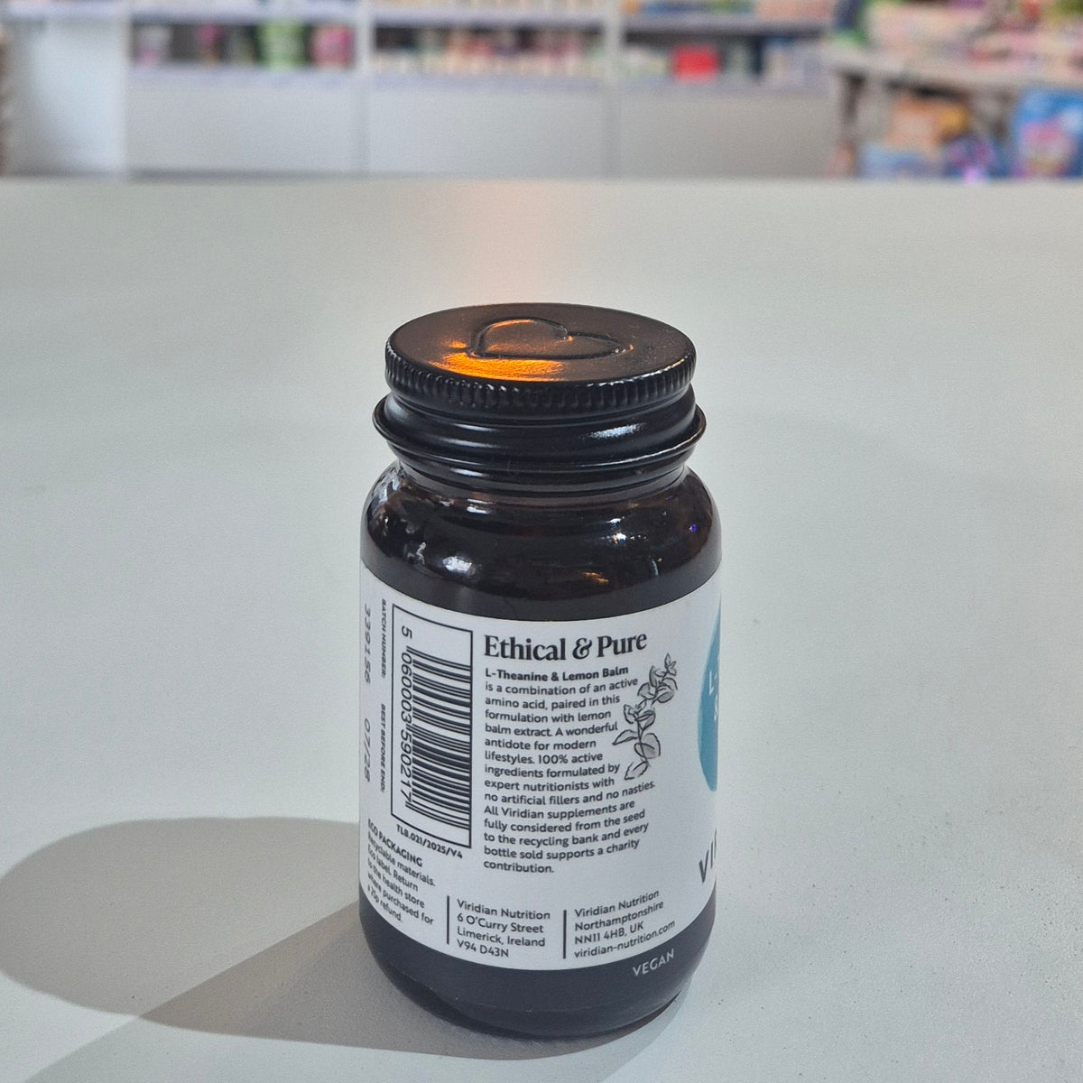  A bottle of Viridian Nutrition L-Theanine & Lemon Balm supplement, with 30 capsules inside, labeled with the product name and strength of 500mg. Bottle labeled 'Ethical & Pure' on a white surface with a blurred background