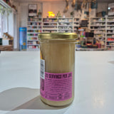 Jar with a pink label held in front of a blurred indoor setting