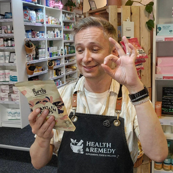 Person in a store holding a product package, wearing a 'Health & Remedy' apron.