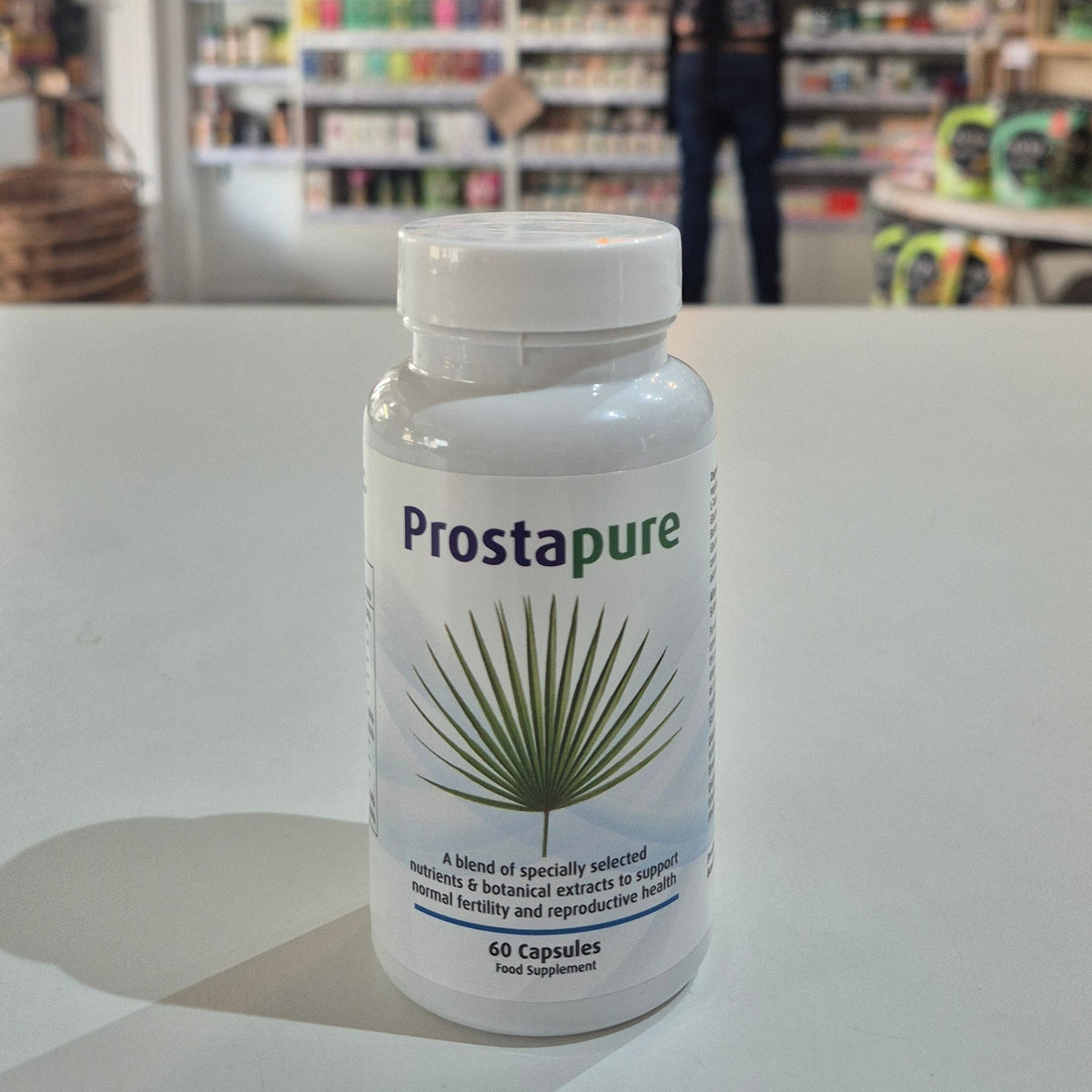 Prostapure supplement bottle on a white surface with a blurred store background