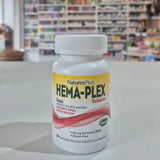 Bottle of Natures Plus Hema-Plex Tablets 42mg Elemental Iron, 30 capsules on a white surface with a blurred indoor background.