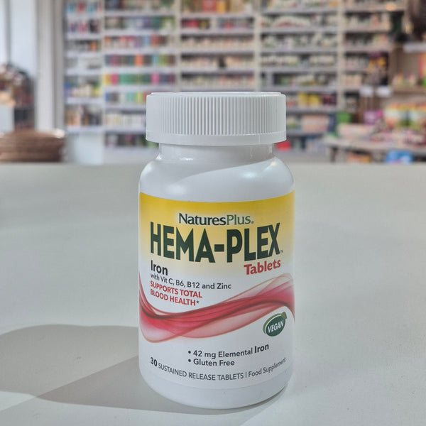 Bottle of Natures Plus Hema-Plex Tablets 42mg Elemental Iron, 30 capsules on a white surface with a blurred indoor background.
