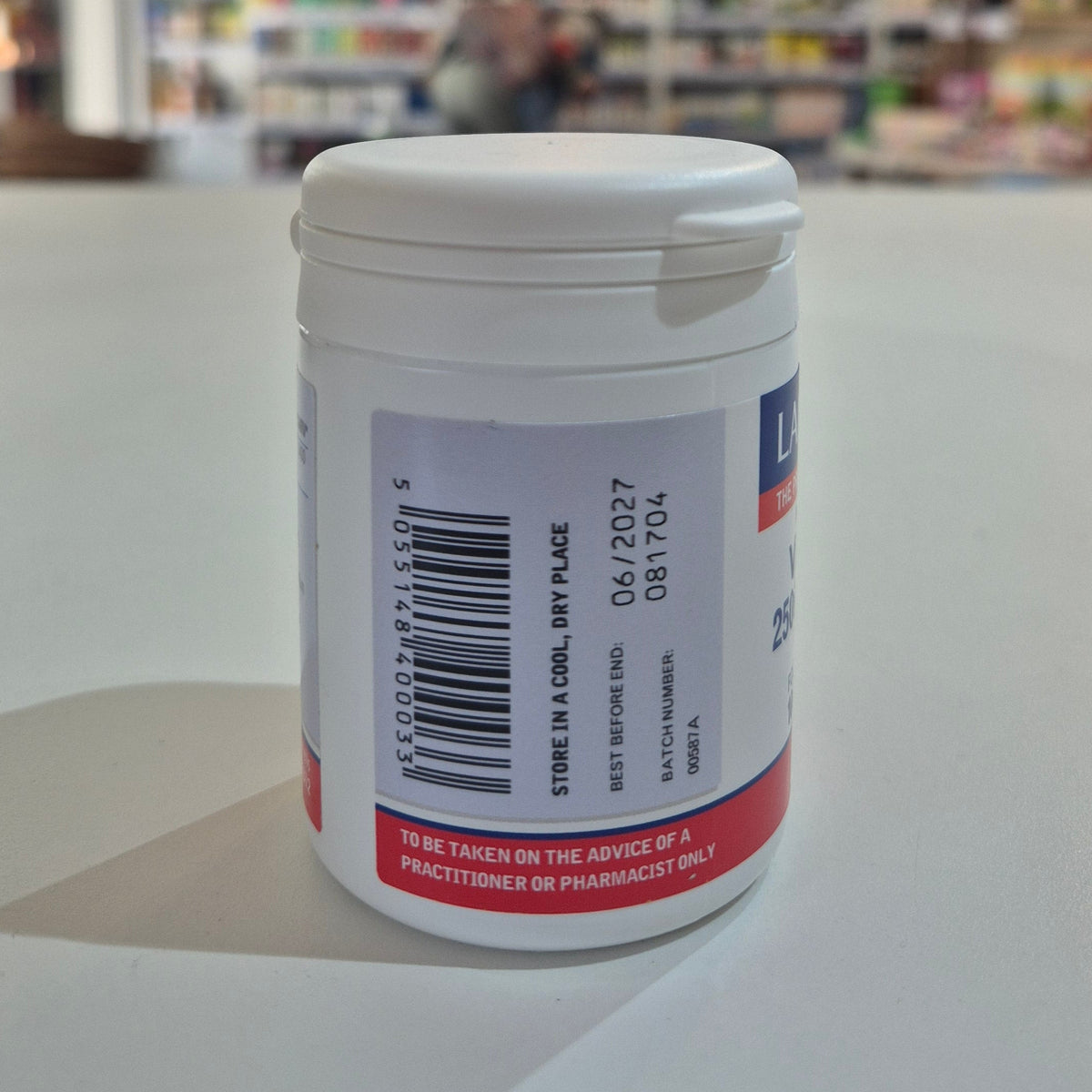 Medication container with label on a white surface, blurred background