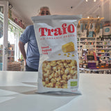 A bag of Trafo Sweet Popcorn organic snacks sits on a white counter in a retail store, with a man standing behind it.