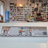 Product packaging with comic-style illustrations on a white wall.