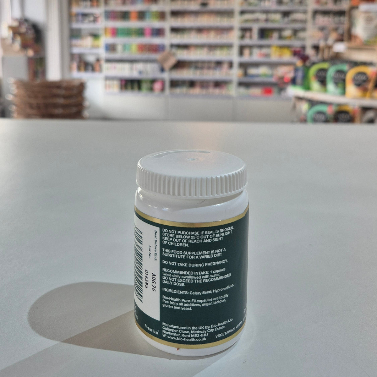 White jar with a green label on a white surface, blurred store shelves in the background