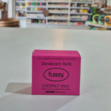 Pink deodorant refill box labeled 'fussy' on a counter with a store background.
