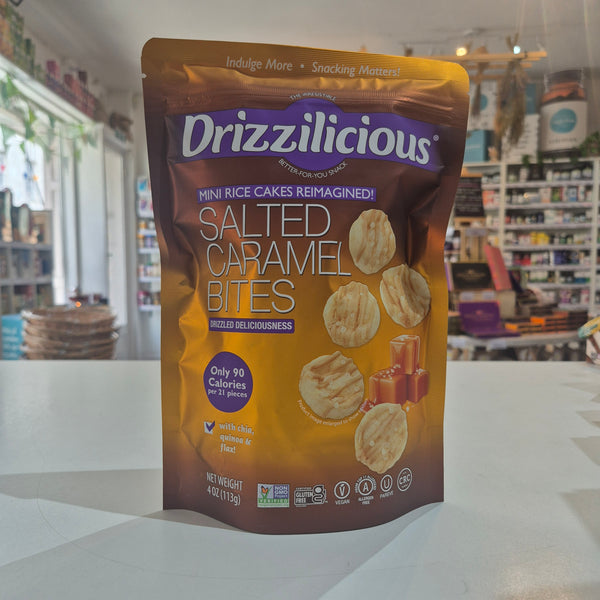 A bag of Drizzilicious Salted Caramel Bites mini rice cakes standing on a white countertop in a blurred retail store setting.