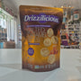 A bag of Drizzilicious Salted Caramel Bites mini rice cakes standing on a white countertop in a blurred retail store setting.