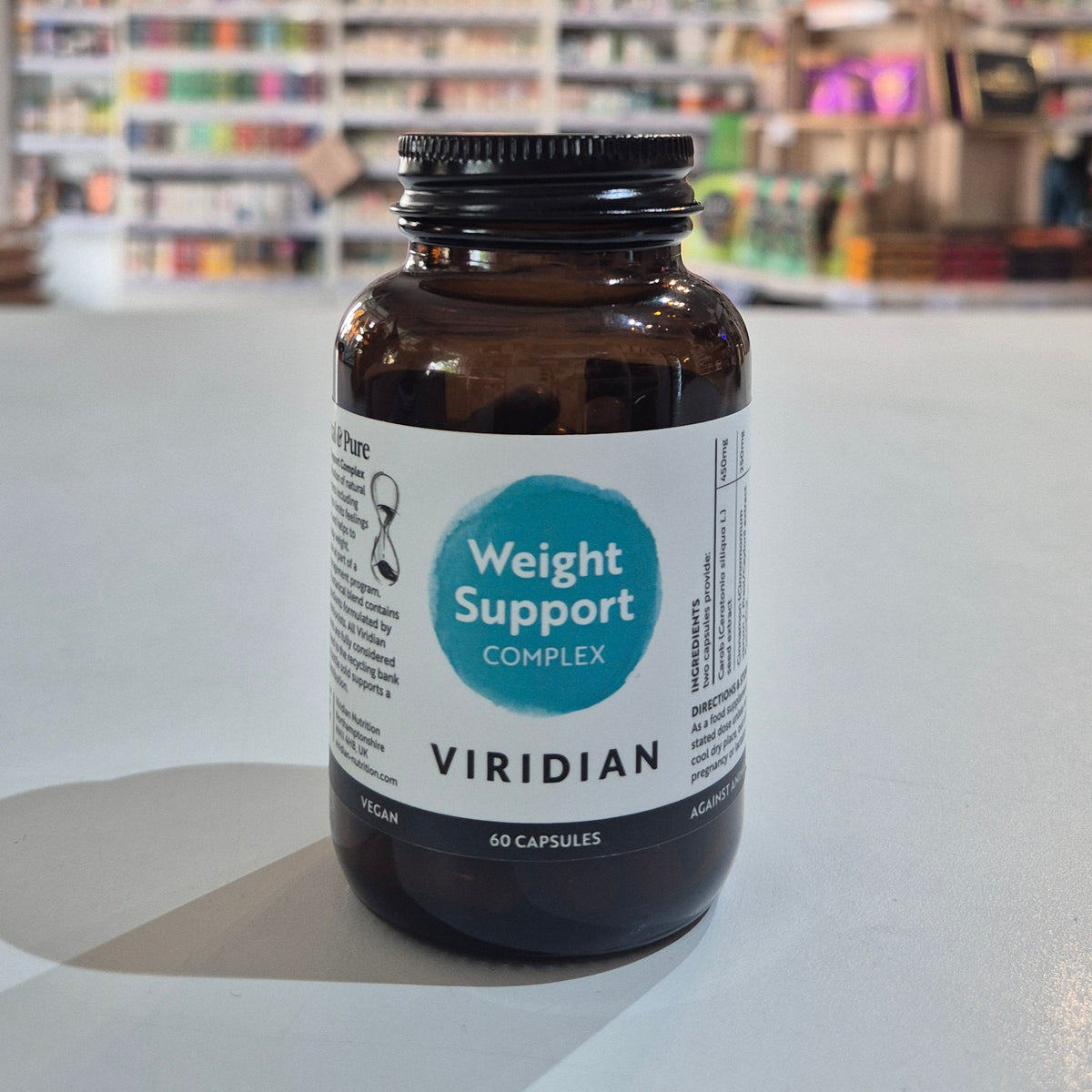 Brown supplement bottle labeled 'Weight Support Complex' by Viridian on a white surface with a blurred store background.