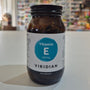 Jar of Viridian Vitamin E capsules on a white surface with a blurred store background