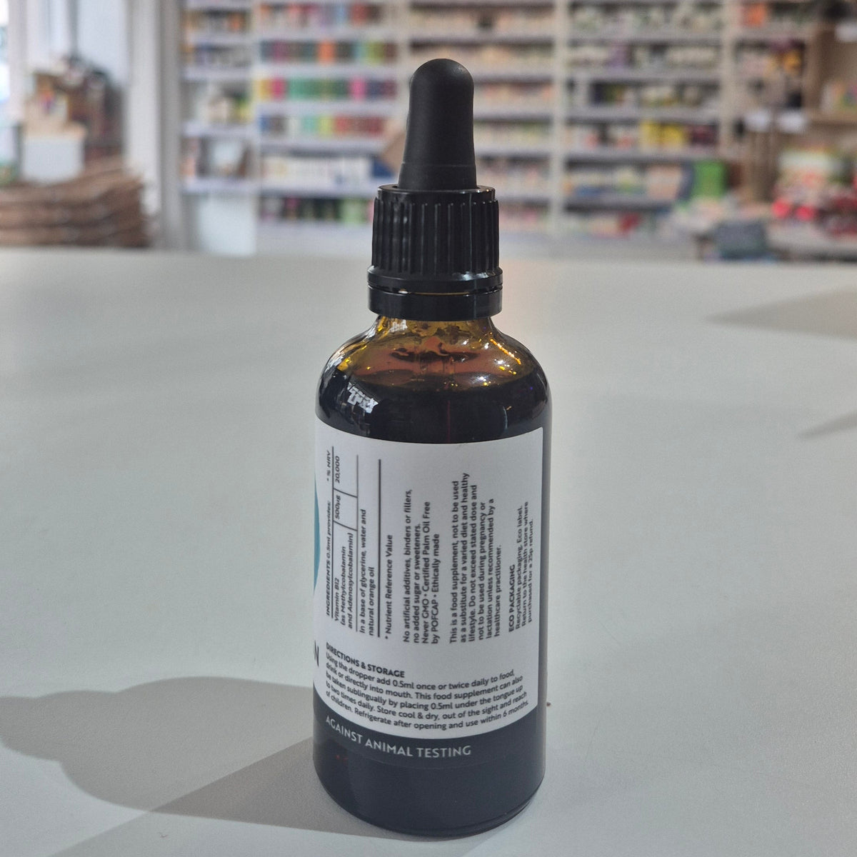 Bottle of Viridian Liquid B12 on a table with a blurred store background. Bottle with dropper on a table in a store setting