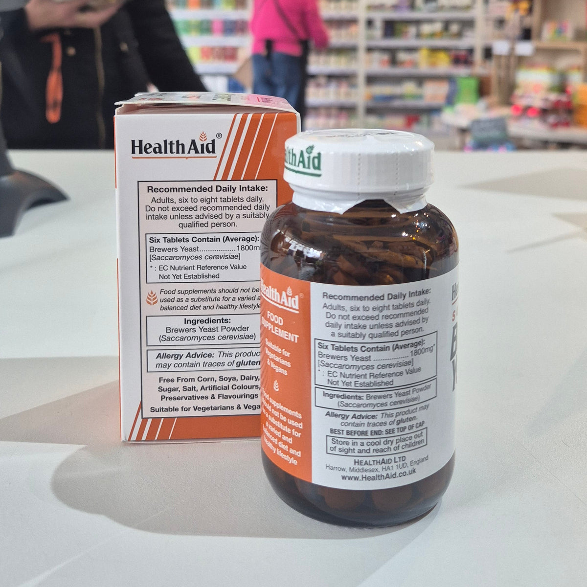 Health Aid supplement bottle and packaging on a counter with a blurred store background