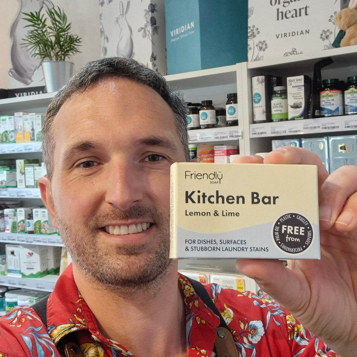 Person holding a bar of Kitchen Bar Lemon & Lime Friendly soap with a brand label in a store setting