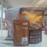 Three snack pouches standing on a white counter in a store: a Dr. trufo bag in the back left, a Drizzilicious bag in the back right, and a Mummy Meegz bag in the front center.