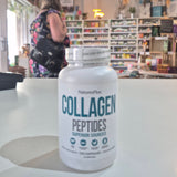 Collagen peptides supplement bottle on a table with a store interior in the background