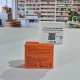 Fussy compostable deodorant refill container and packaging on a table with a blurred store background. White container with a QR code label on a red box in a store setting
