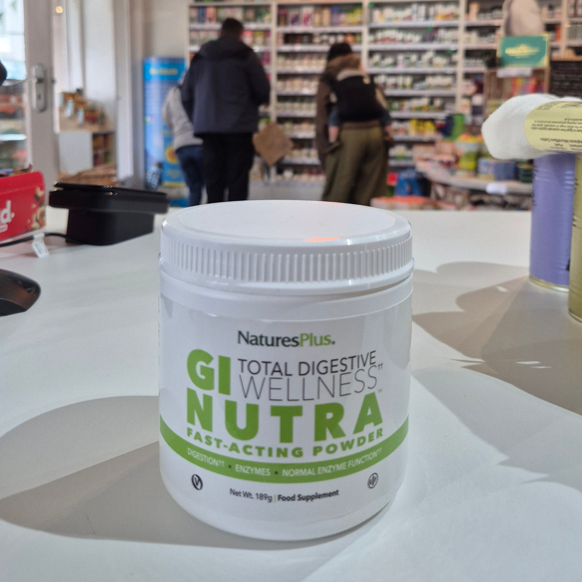 Container of 'Wellness Nutra' product with a store interior in the background