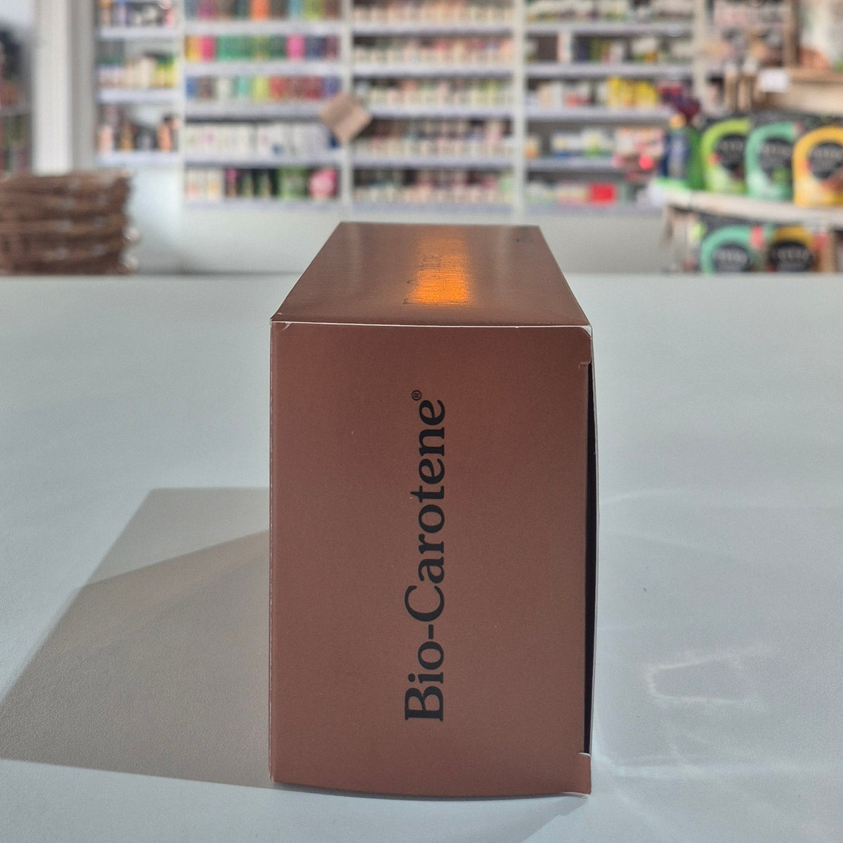 Brown box with 'Bio-Carotene' branding on a light gray surface with a blurred store background.