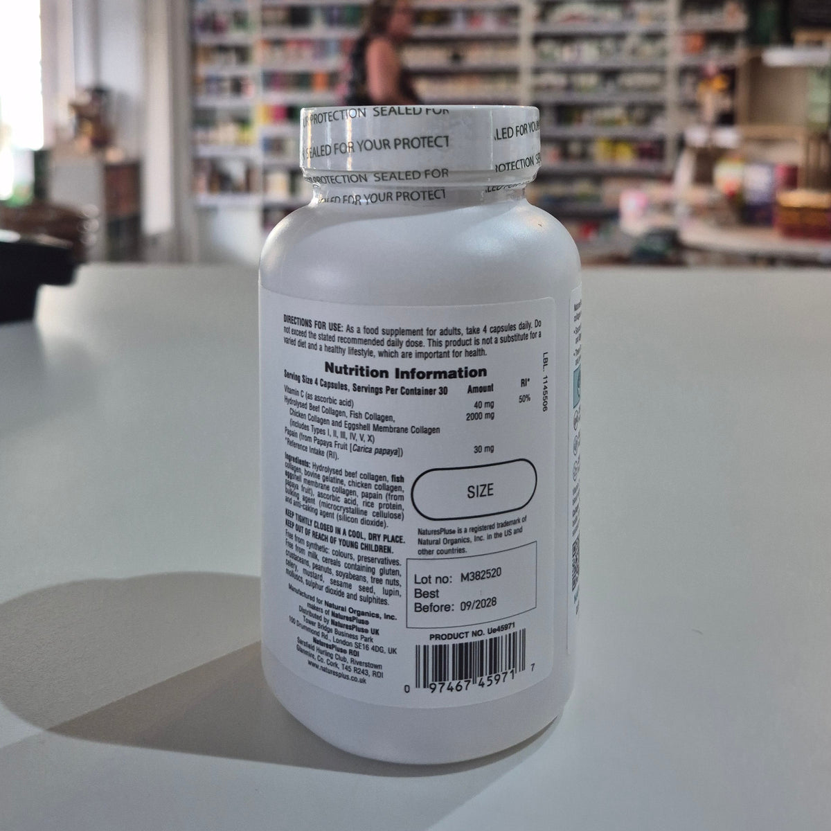Collagen peptides supplement bottle on a table with a store interior in the background. Supplement bottle with label on a table in a store setting