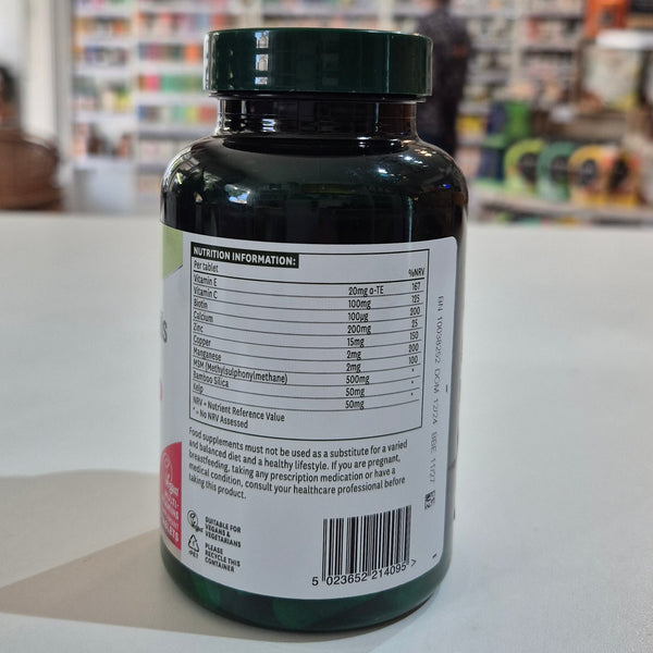 Green supplement bottle with label on a white surface, blurred store background