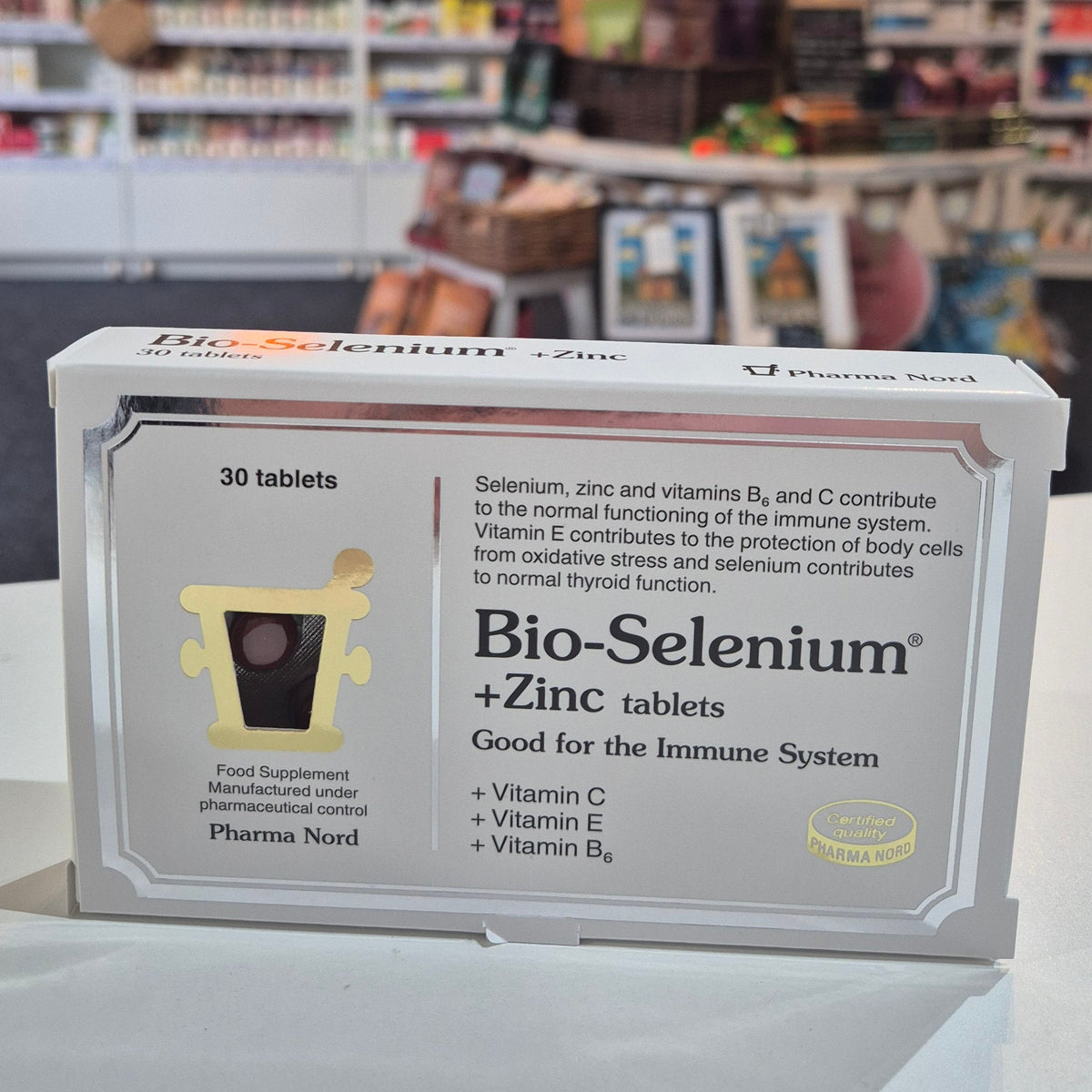Supplement box labeled 'Bio-Selenium' on a white surface with a blurred background of shelves.