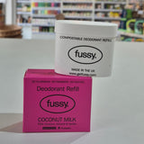 Fussy deodorant refill container and packaging on a table with a blurred store background