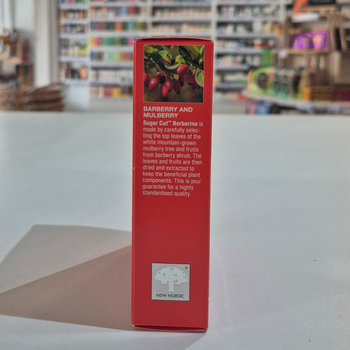 Red box with text and New Nordic logo on a white surface with blurred shelves in the background