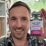 Man holding a bottle of Nature's Truth Hair, Skin & Nails Gummies in a store setting.
