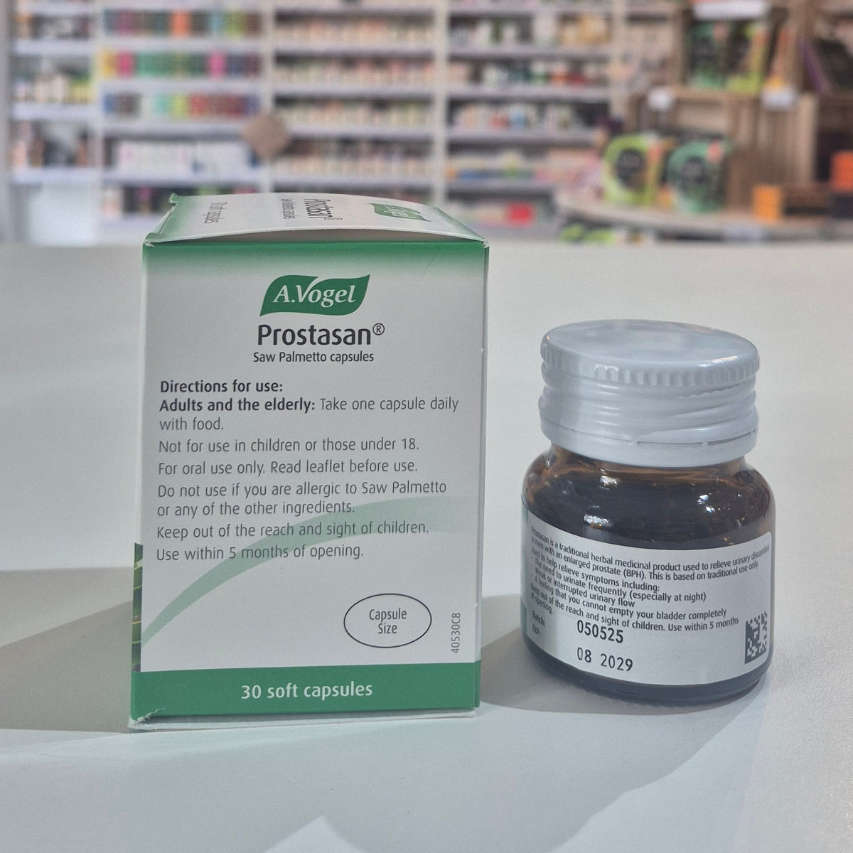 A bottle and its packaging of A.Vogel Prostasan on a surface with a blurred store background.