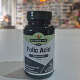 Natures Aid Folic Acid supplement bottle on a white surface with a blurred indoor background
