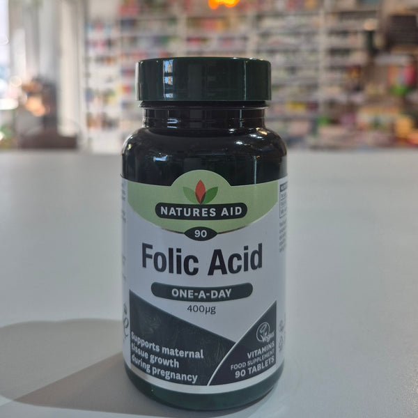 Natures Aid Folic Acid supplement bottle on a white surface with a blurred indoor background
