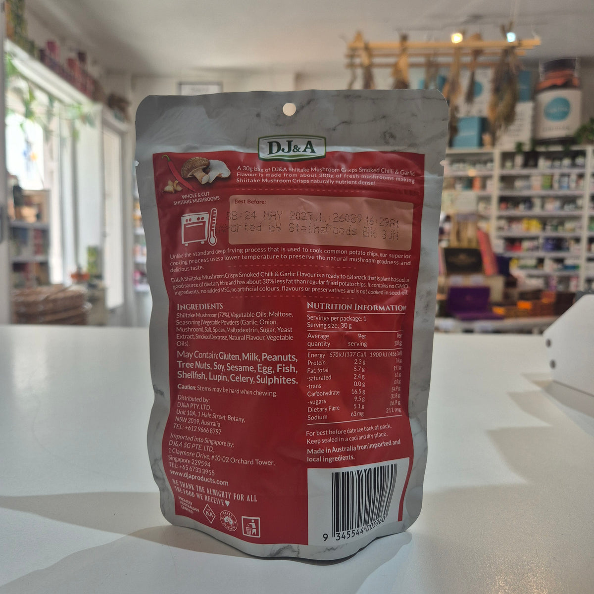 The back of a D.J & A Mushroom pouch, showing the ingredients, nutrition facts, and barcode, placed on a white counter in a store.