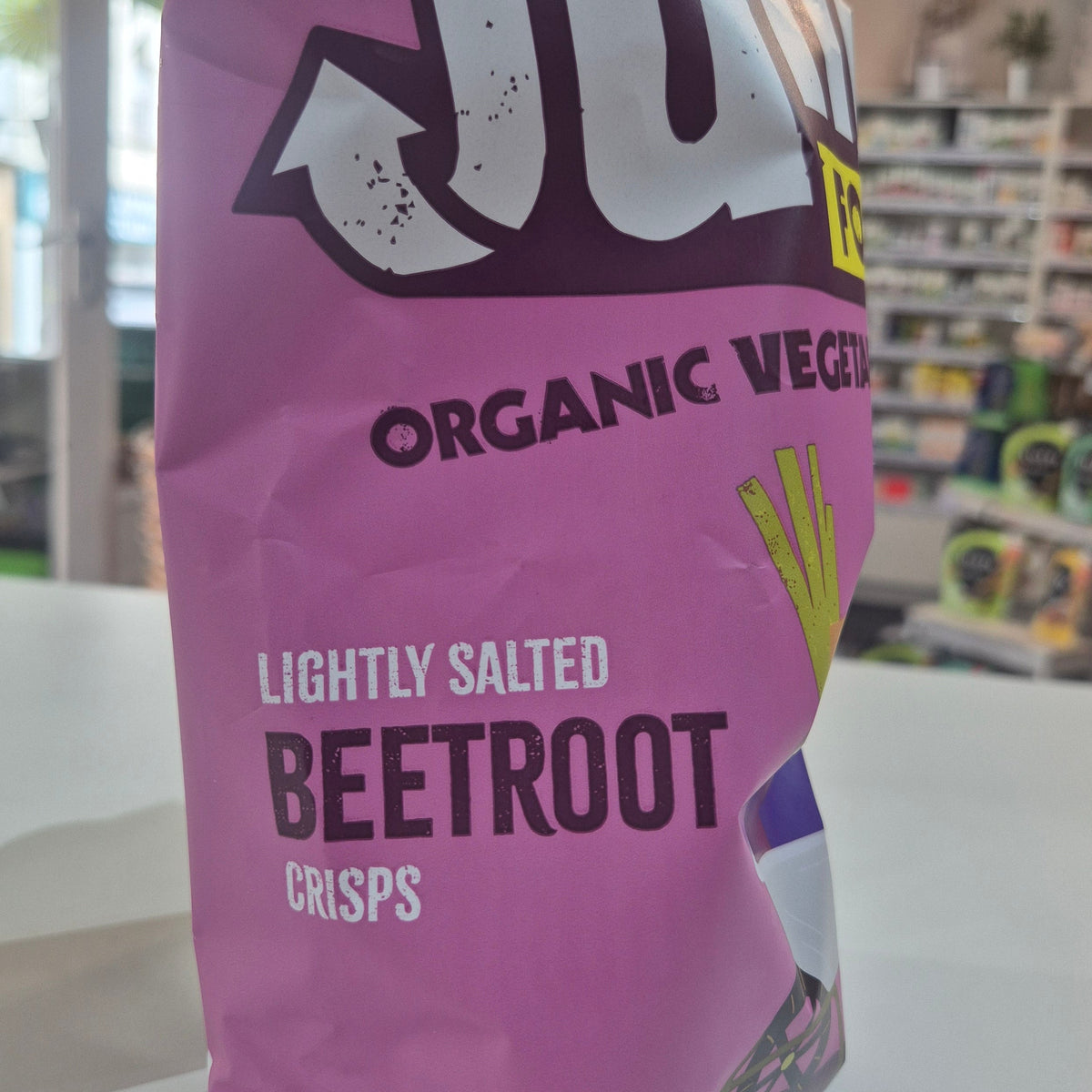 Purple bag of organic beetroot crisps with visible branding in a store setting