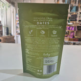 Green package of pistachio crisp milk chocolate dates on a white surface with a blurred store background.