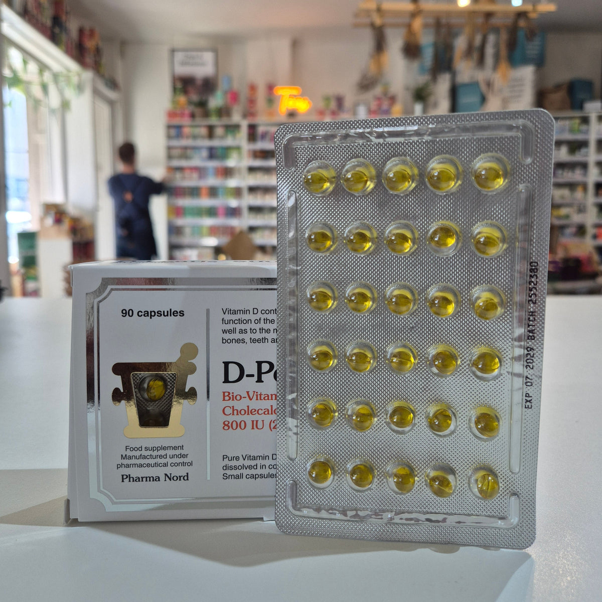 Box of D-Pearls Vitamin D supplement with sun design on a white background. Bio-Vitamins with capsules in a store setting
