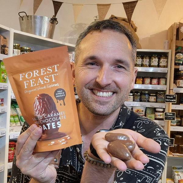 Man holding a package of Forest Feast chocolate treats in a store setting