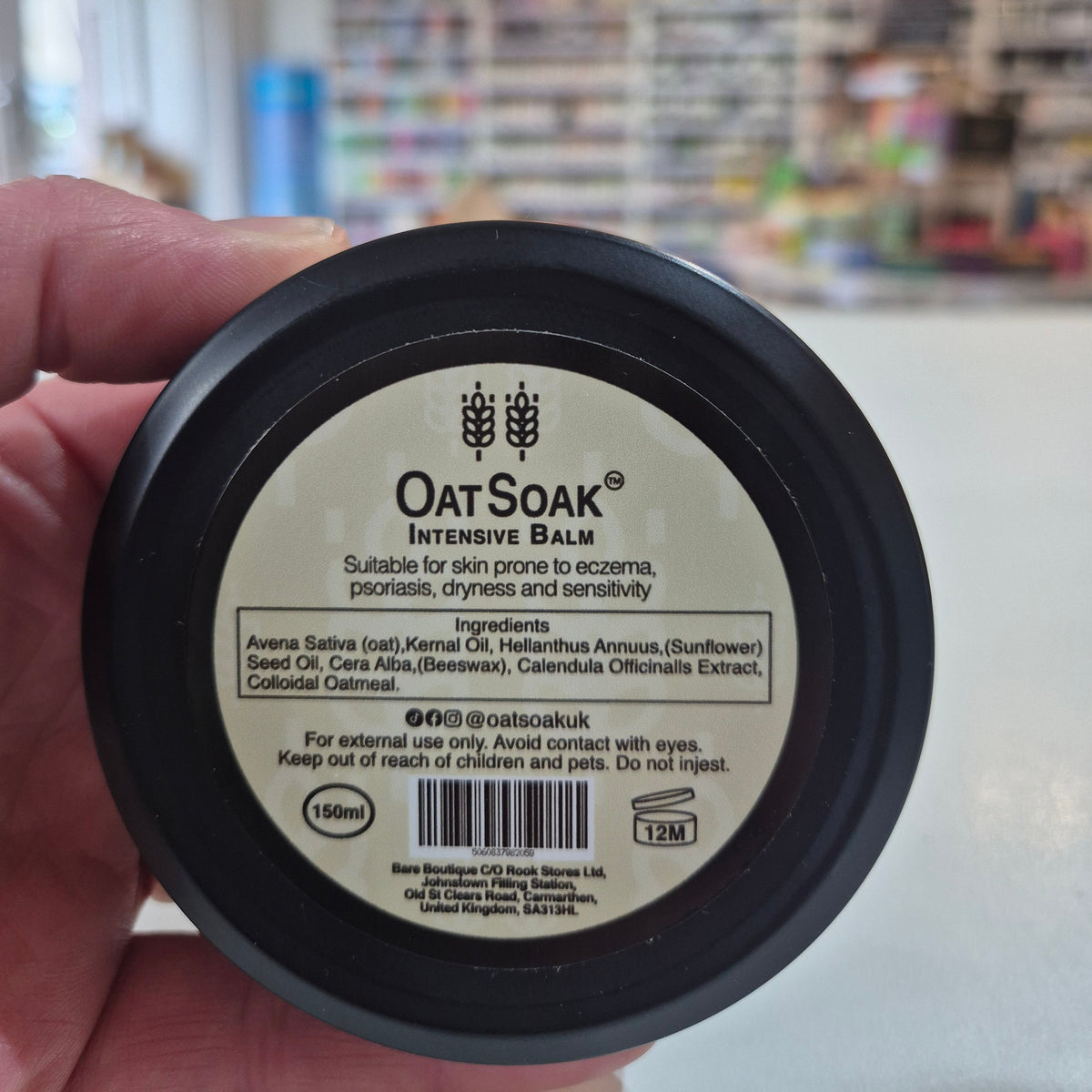 Person holding a jar of Oats & Soap balm with a blurred store background
