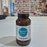 Bottle of Viridian Magnesium Citrate Powder on a white surface with a blurred store background.