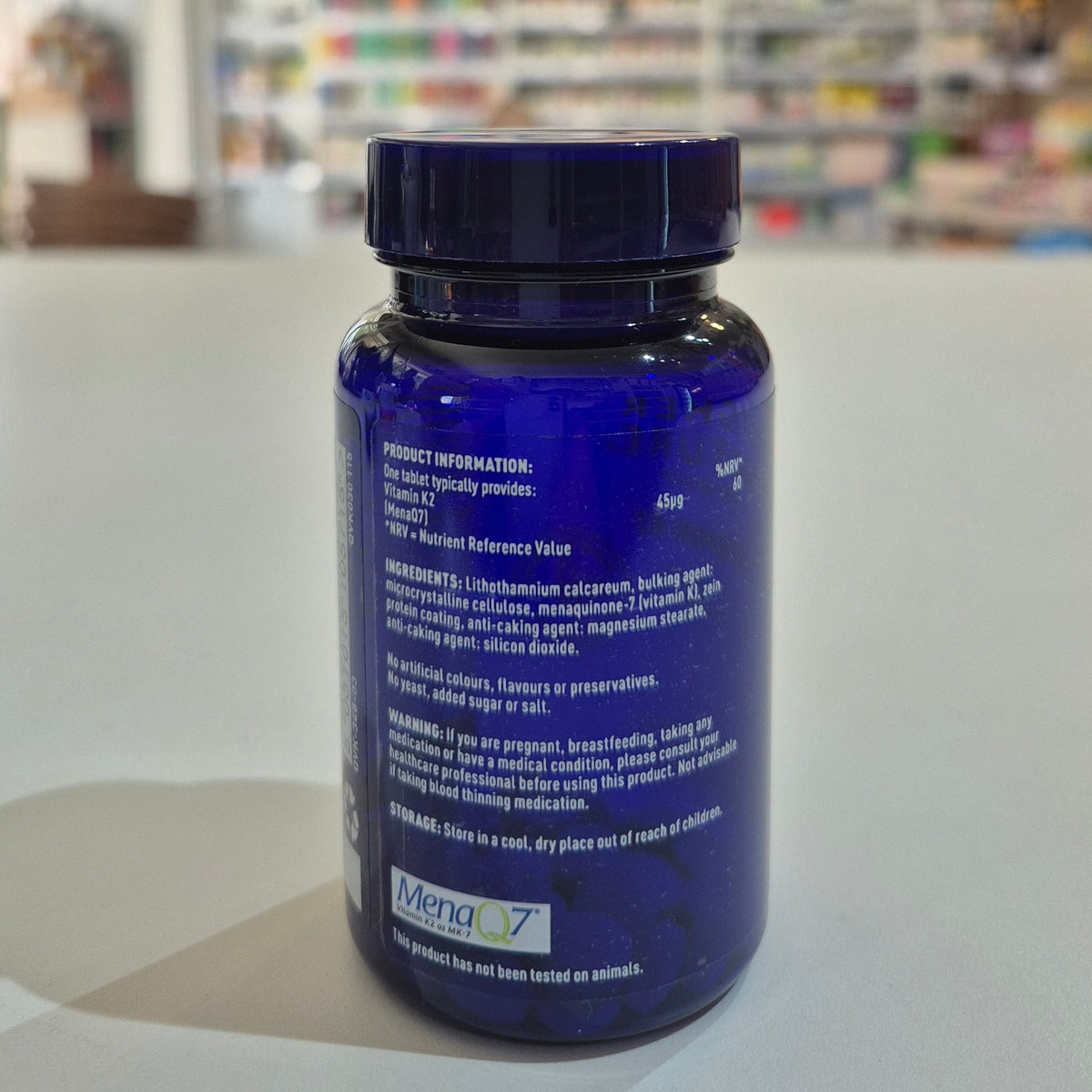 Blue supplement bottle with text on a white surface