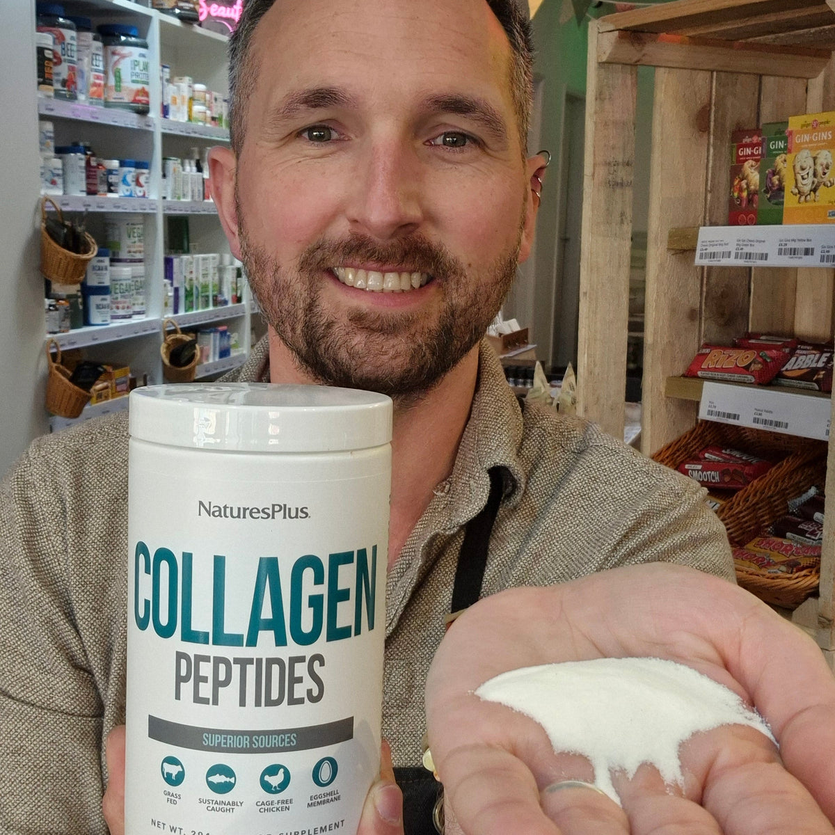 Man holding a container of NaturesPlus Collagen Peptides in a store setting.