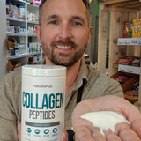 Man holding a container of NaturesPlus Collagen Peptides in a store setting.