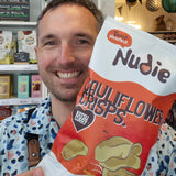 Person holding a large bag of Nudie's potato chips in a store setting