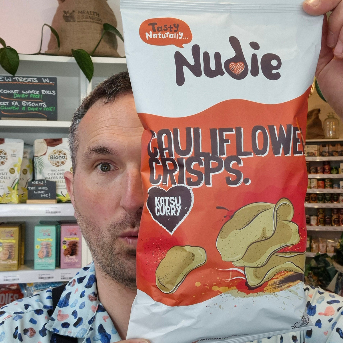 Person holding a Nudie Crisps package in a store setting