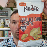 Person holding a Nudie Crisps package in a store setting