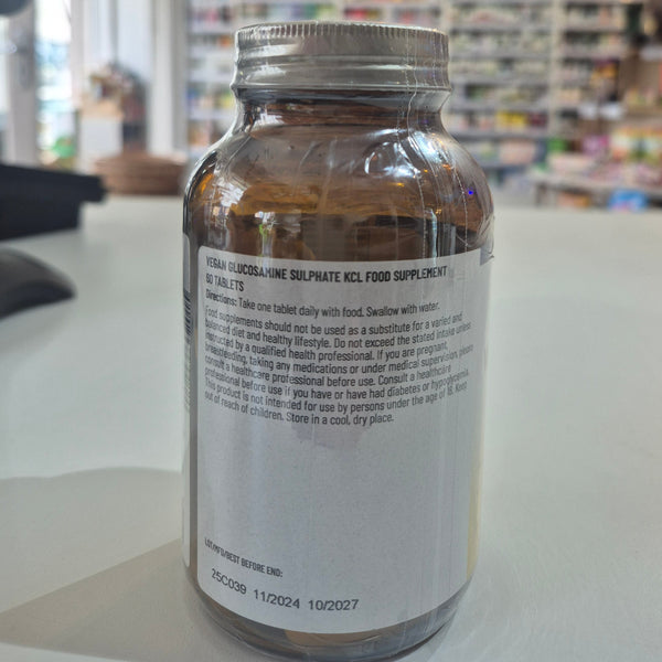 Glass bottle with label on a white surface, blurred store interior in the background