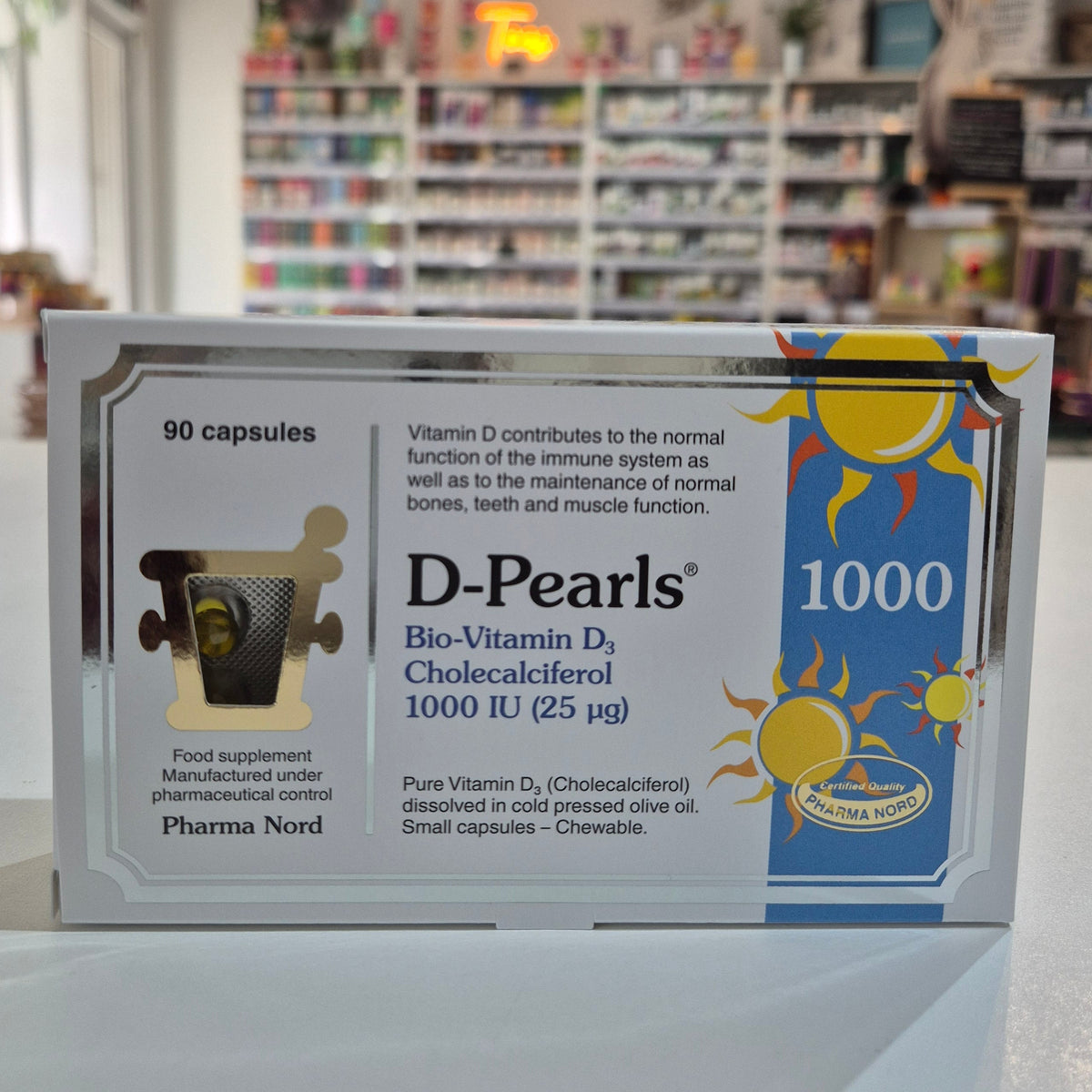 Box of D-Pearls 1000 capsules with a blurred bookstore background