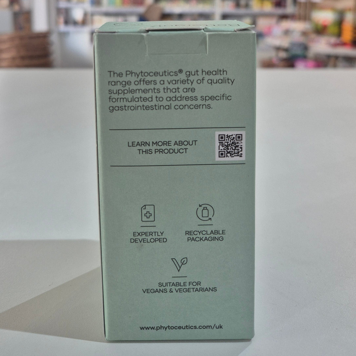 Green supplement box with text and QR code on a light gray surface