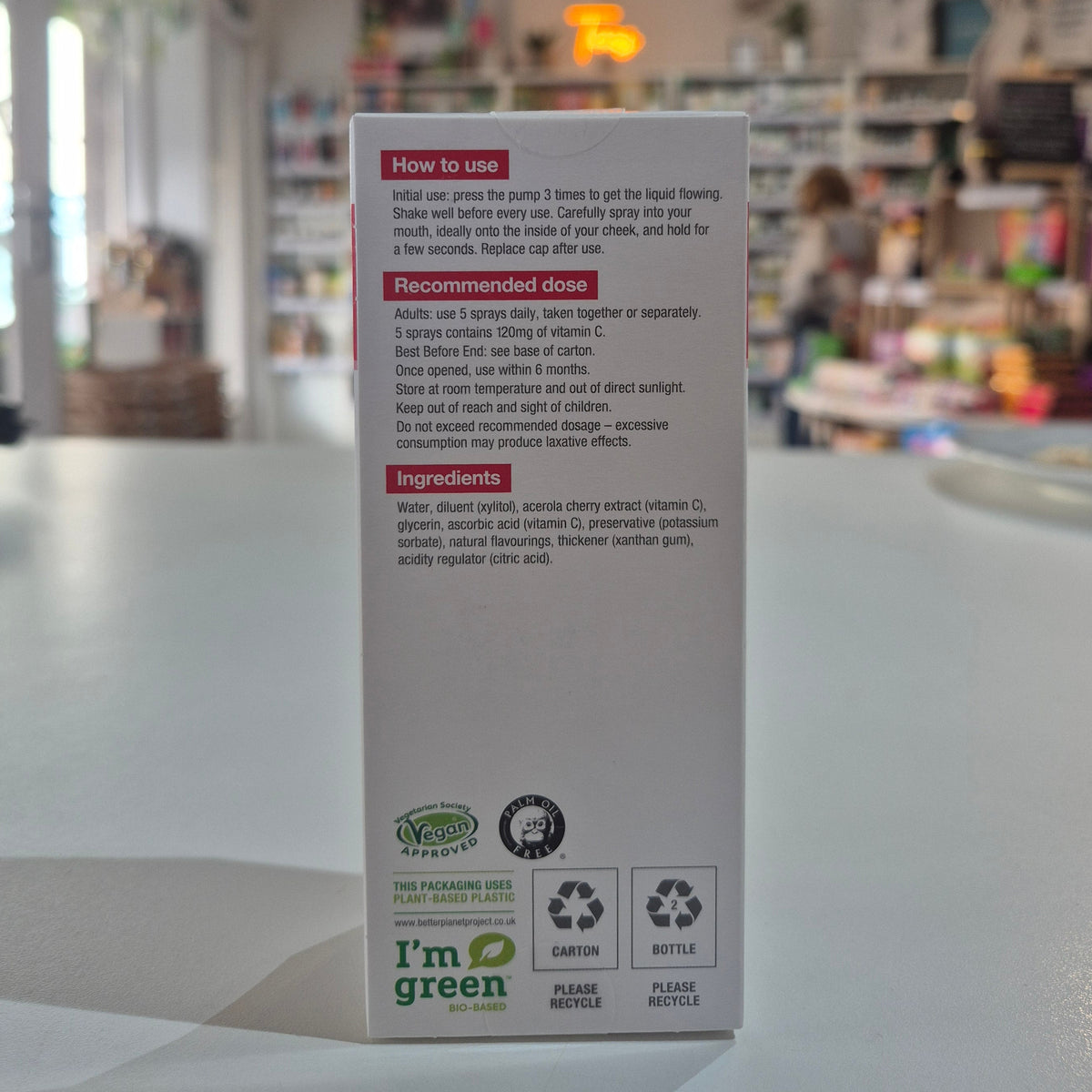 Box of BetterYou Vitamin C Daily Oral Spray on a counter with 'I'm Green' label on a blurred background